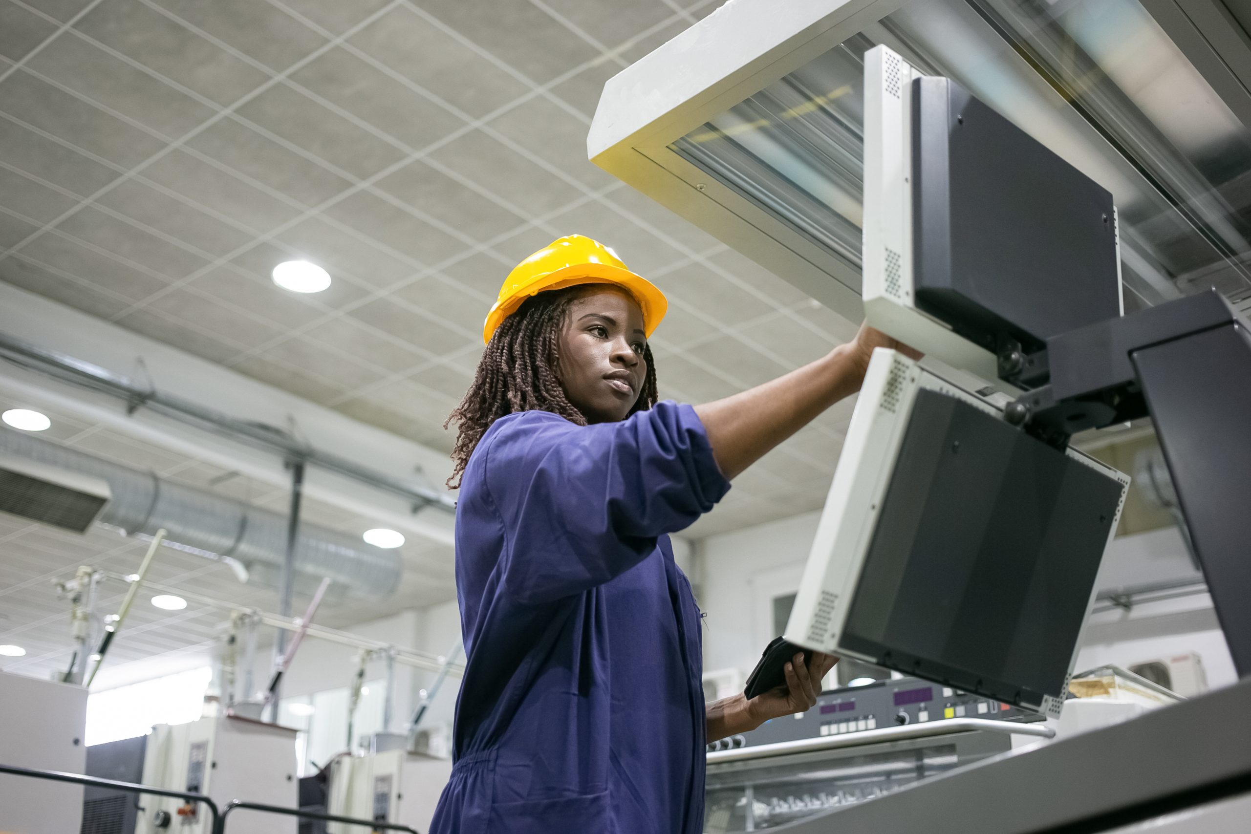 Female factory worker operating industrial machinery by touching a digital control board